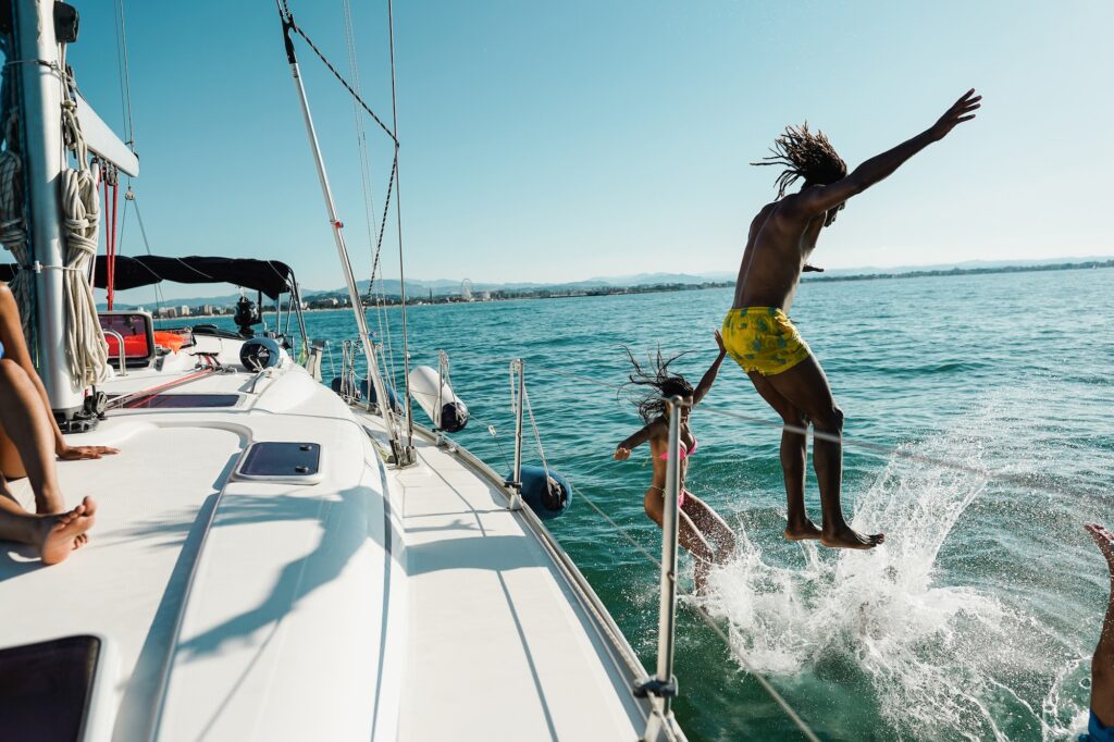 Happy friends diving from sailing boat into the sea - Focus on girl face