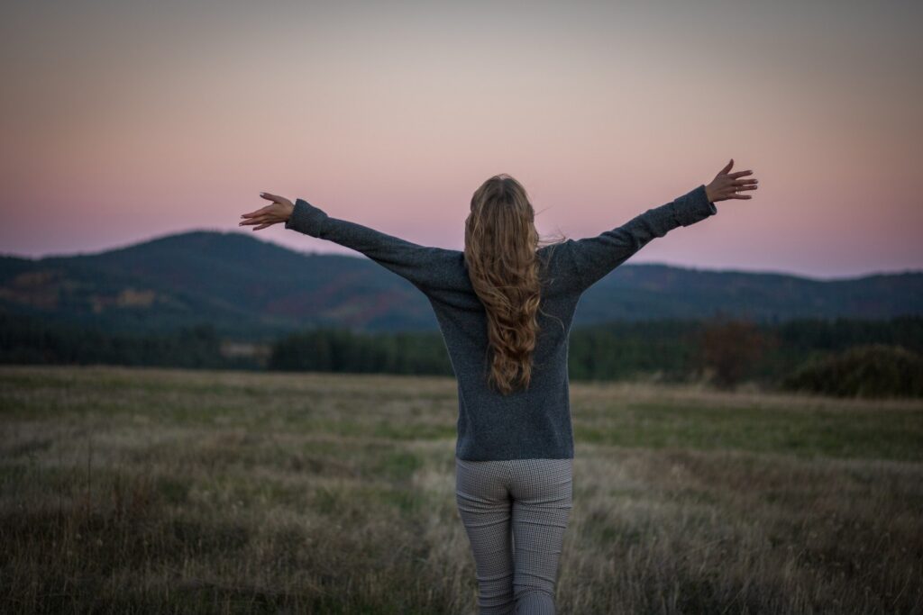 a person with the arms raised in a field