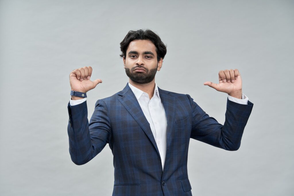 Confident indian arab business man isolated on beige pointing at himself.