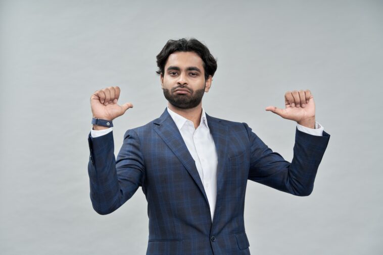 Confident indian arab business man isolated on beige pointing at himself.