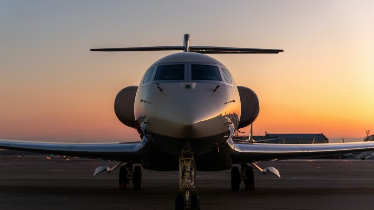 Scenic front view modern luxury expensive private jet plane parked airport taxiway hangar warm