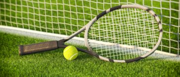 Tennis racket and tennis ball on a grass of tennis court.