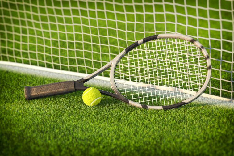 Tennis racket and tennis ball on a grass of tennis court.